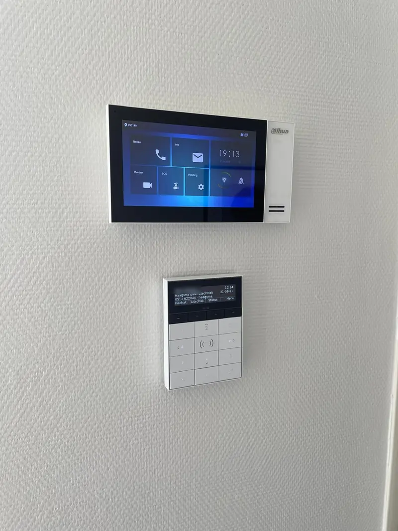 Video-intercom en alarmbediendeel aan de wand van een woning